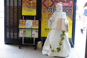 女神の彫刻に扮した女性。全身白く、ドレス姿でアコーディオンを抱えている。